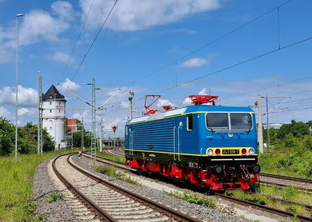 einzelne blaue Elektrolok BR243 auf der Strecke und im Hintergrund ist ein turmähnliches Stellwerkhaus zu sehen